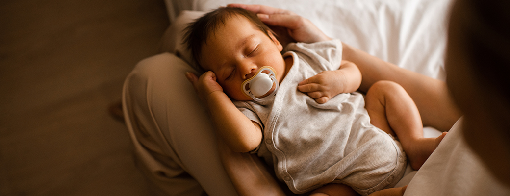 Image of infant baby asleep on adult lap